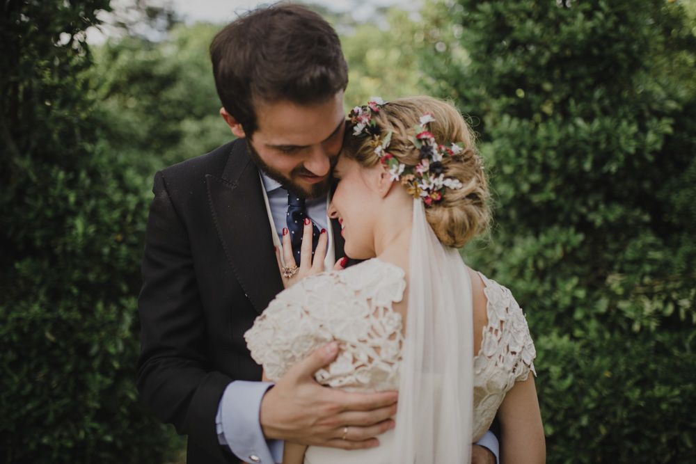 A tender moment between newlyweds surrounded by green foliage.