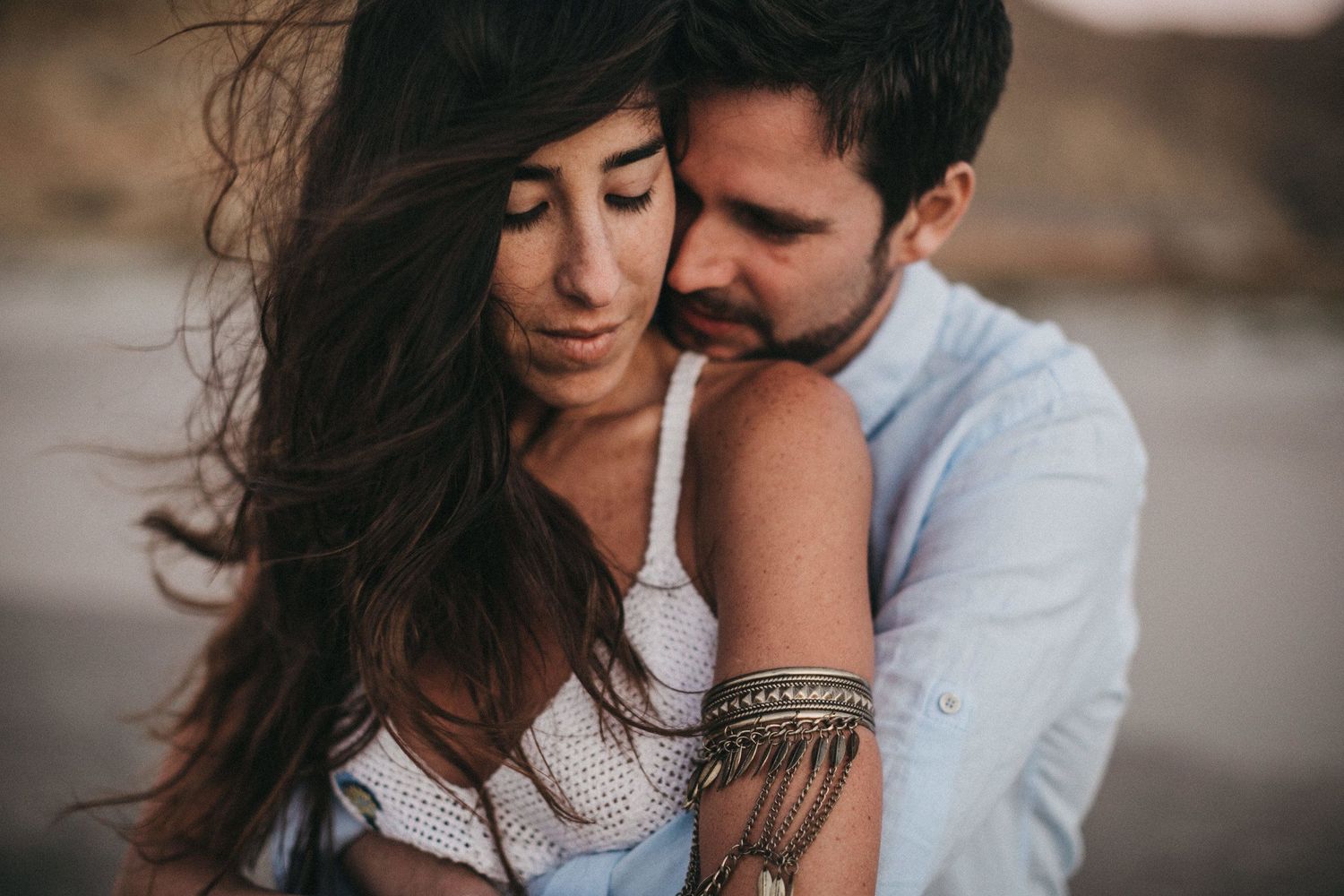 Intimate couples portrait with windswept hair against a moody backdrop.