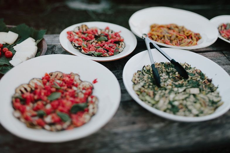 Festive plates of colorful appetizers and snacks arranged on a dark wooden table.