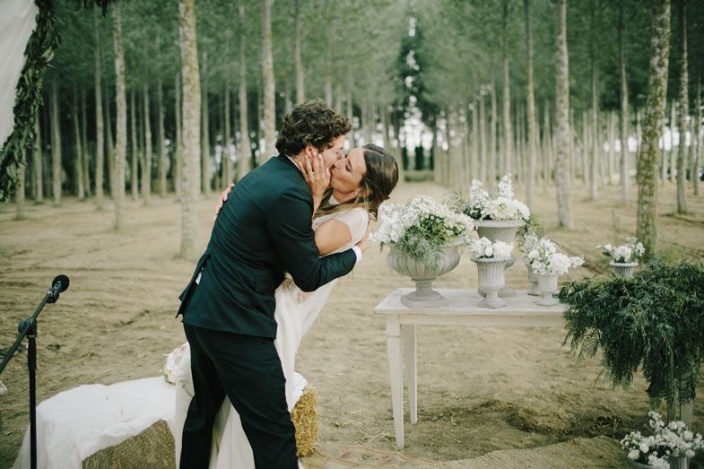 Romantic wedding moment captured in a serene aspen forest with white decorations.