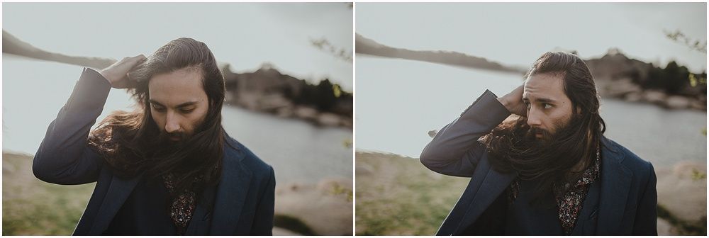 Portrait in dark tones showing a well-dressed figure with beard against coastal background.