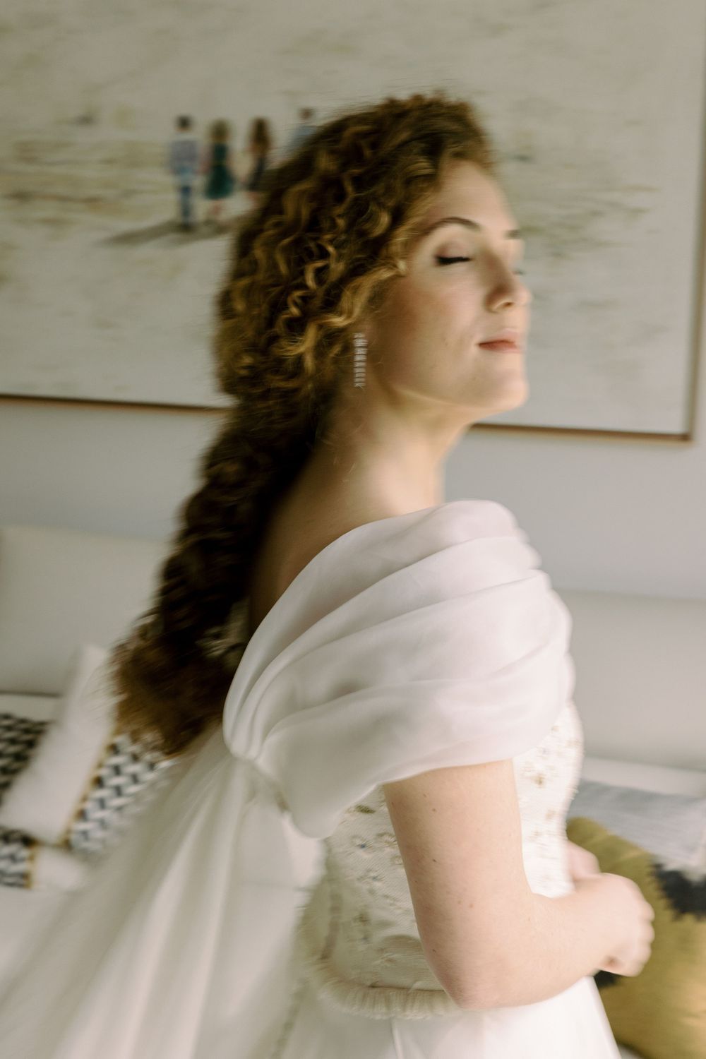 A side profile view of a bride in a white wedding dress with elegant curled hair.