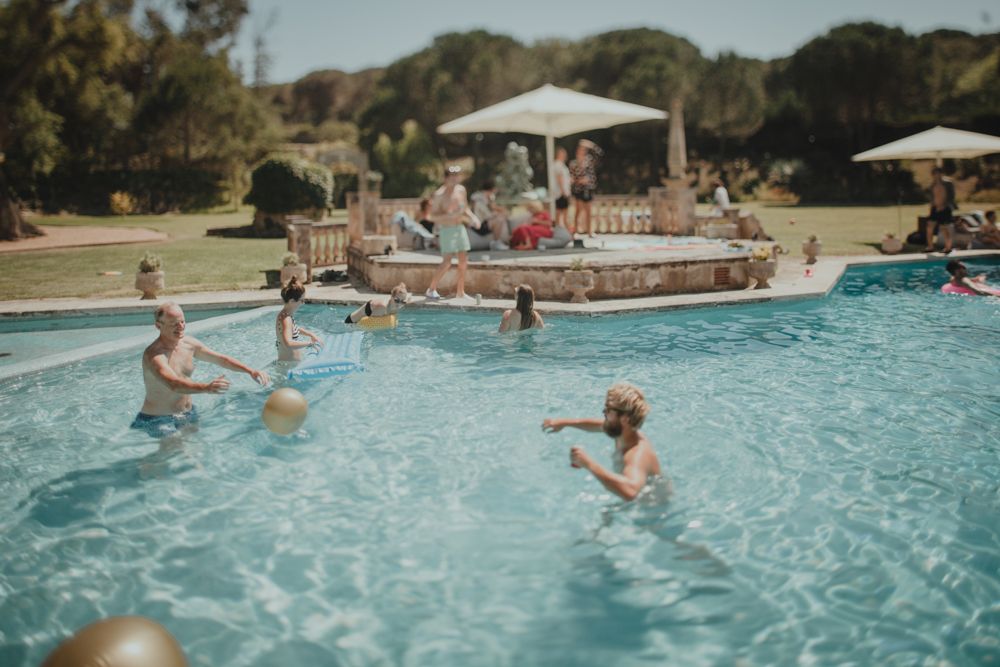 People playing and splashing in outdoor swimming pool on sunny day.