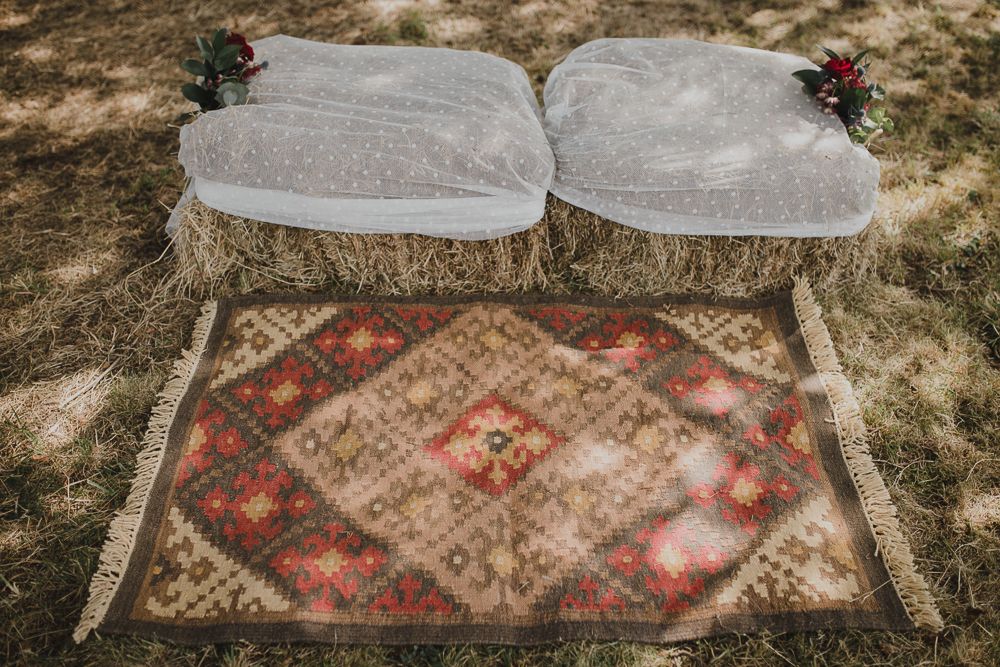 Two plush cushions arranged on a vintage patterned rug in an outdoor setting.