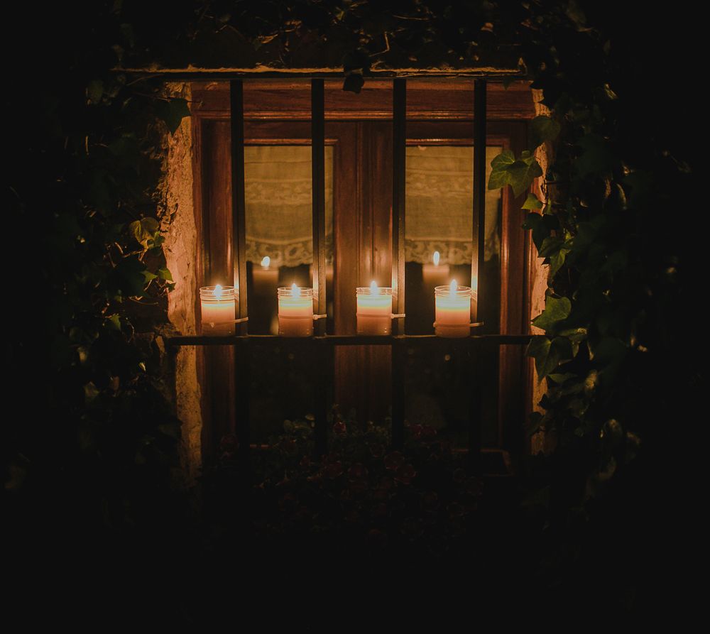 Glowing candles illuminate a wooden window frame creating a cozy atmosphere.