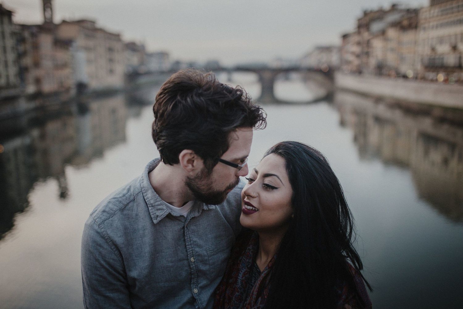 Intimate couple portrait with Florentine bridge and river in background.