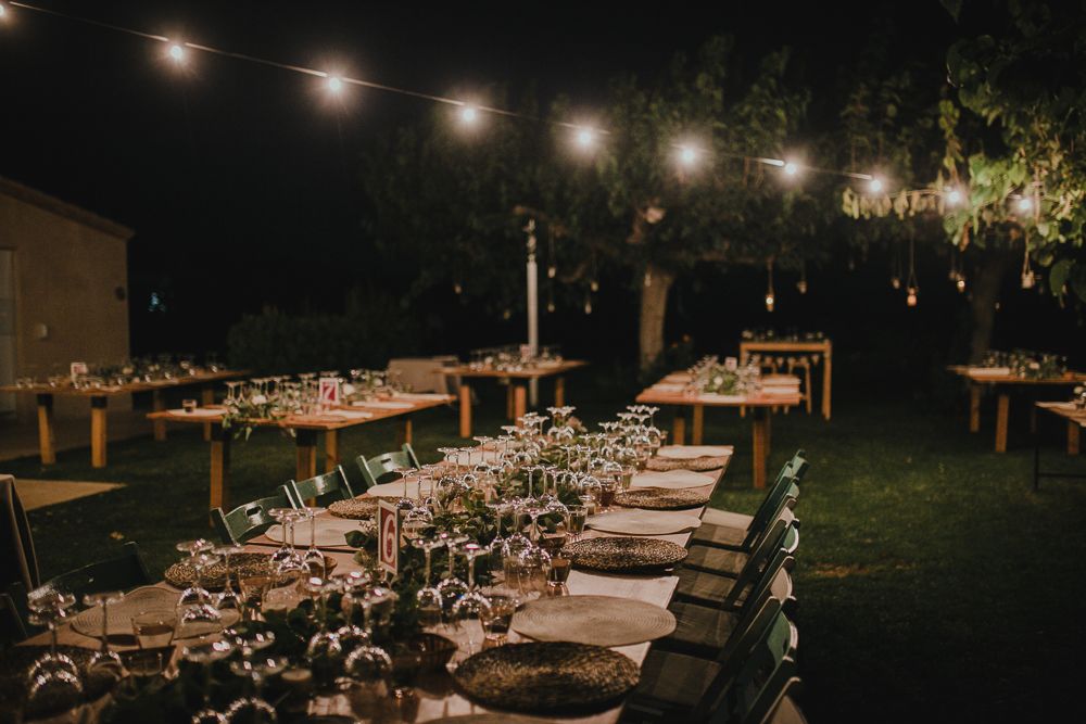 An outdoor wedding reception table set under string lights at dusk.