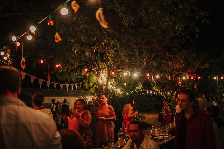 An outdoor evening party decorated with string lights and colorful bunting.