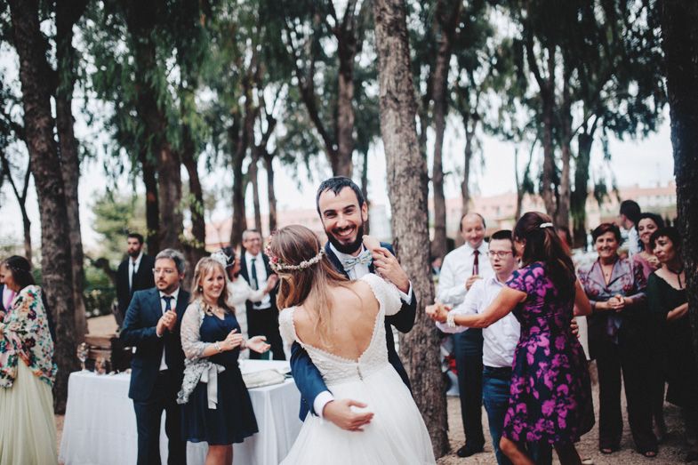 Couple dancing surrounded by wedding guests at outdoor forest reception.