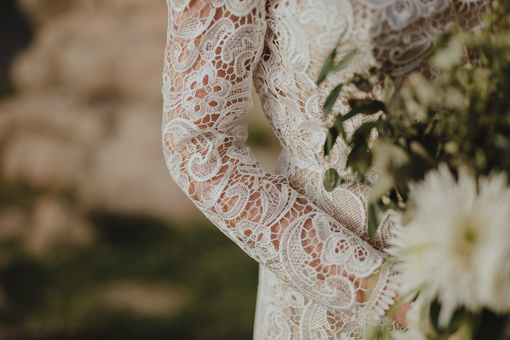 Delicate lace sleeve detail of a wedding dress with intricate floral patterns.