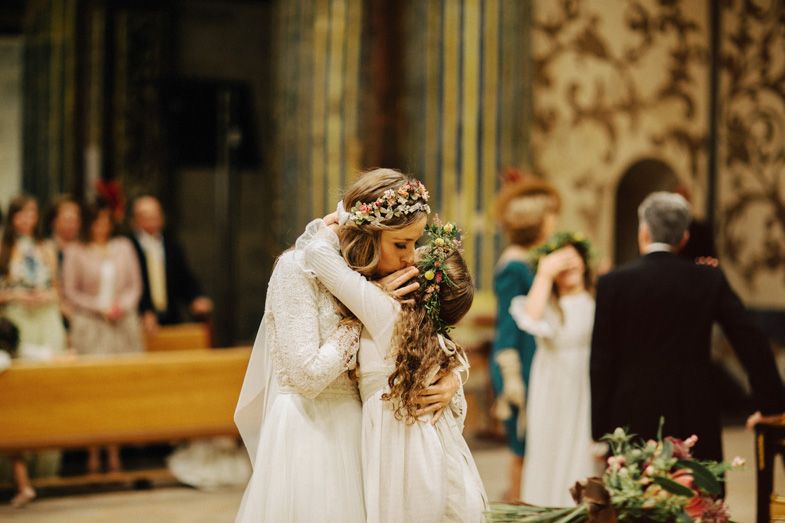Two people embrace during an emotional moment at their wedding ceremony in a grand church setting.