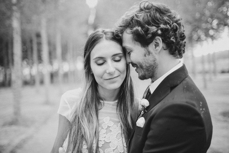Intimate black and white portrait of newlyweds sharing a tender moment in a forest setting.