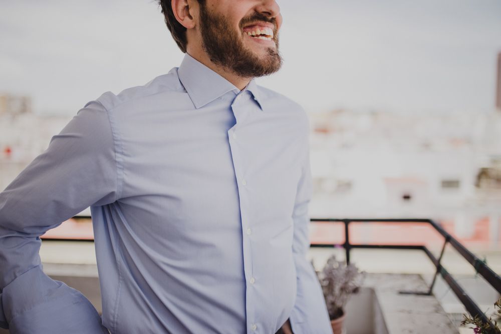 A light blue dress shirt worn on a balcony with a cityscape backdrop.