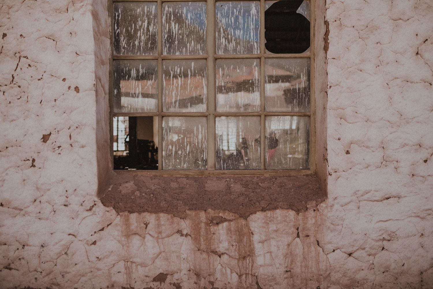 Weathered window frame in aged adobe wall shows rustic architectural detail.