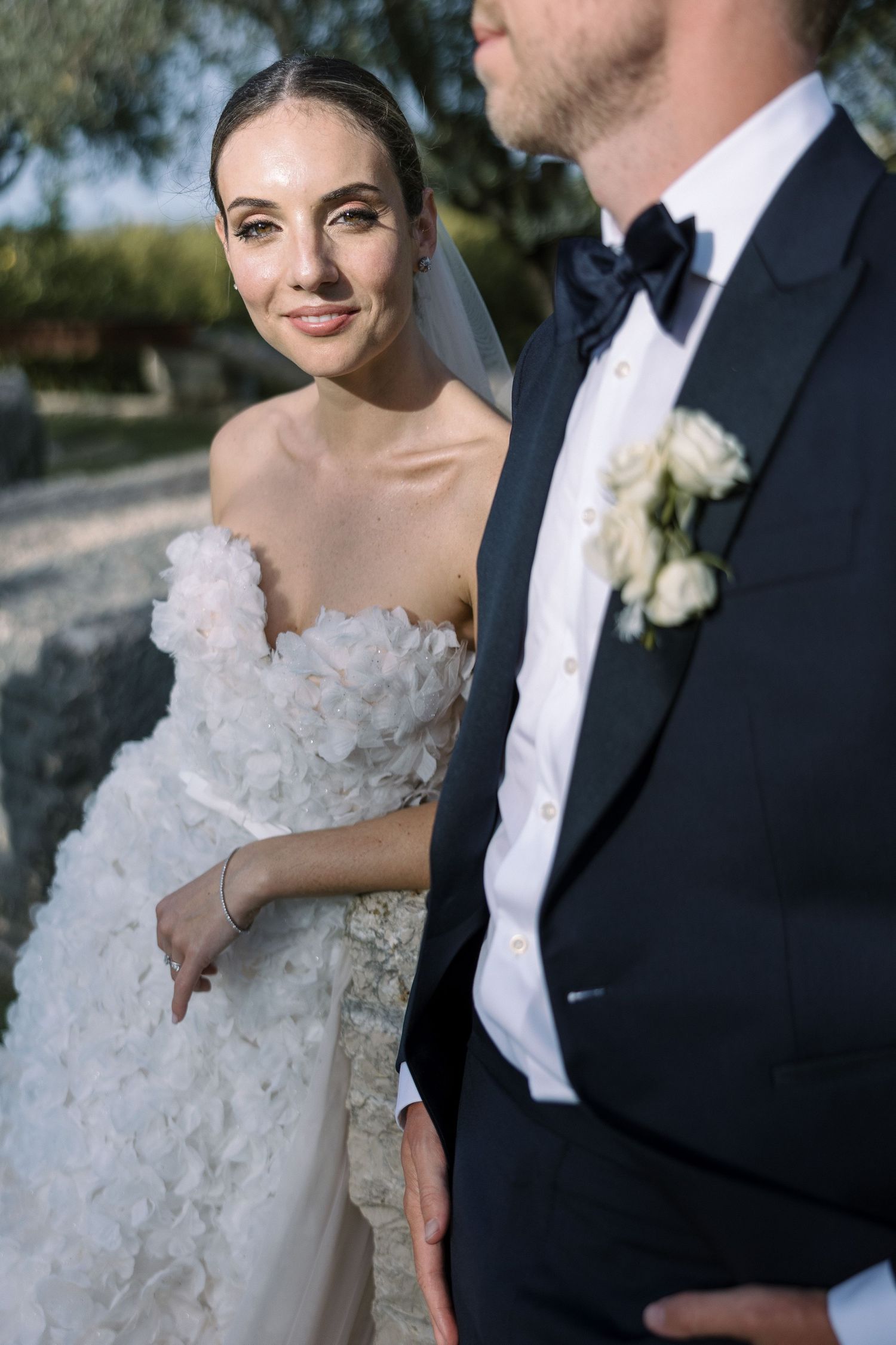 Romantic outdoor wedding portrait featuring elegant bridal gown and classic tuxedo.