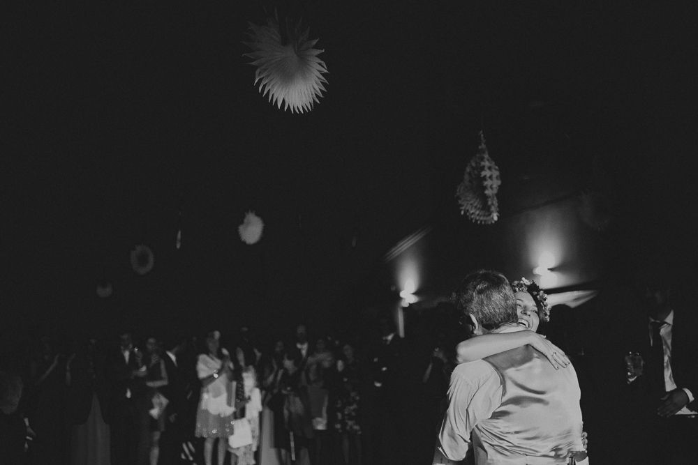 Silhouetted figures dancing under illuminated decorations at a nighttime event.
