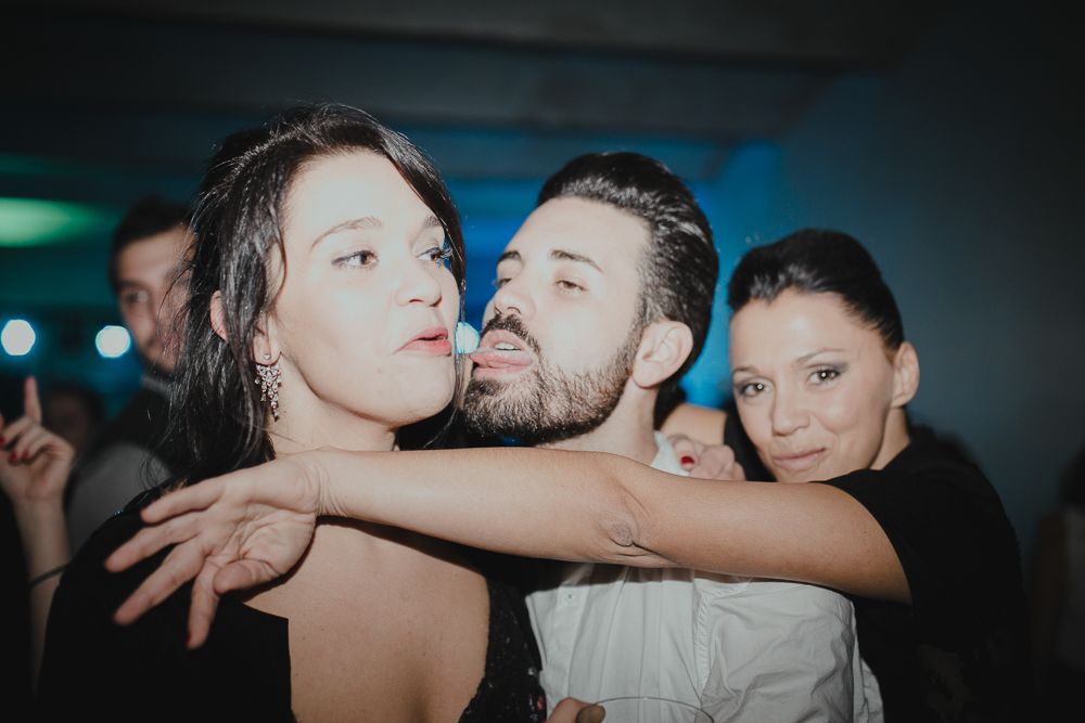 Party guest celebrates joyfully at dimly lit reception venue.