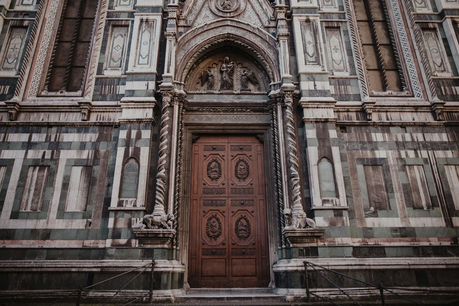 Ornate wooden door entrance of a Gothic cathedral with detailed stone carvings and architectural elements.