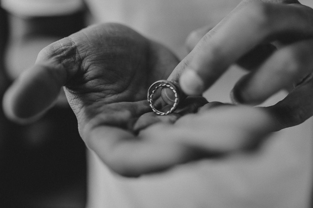 Close-up black and white photo of hands holding a delicate ring.