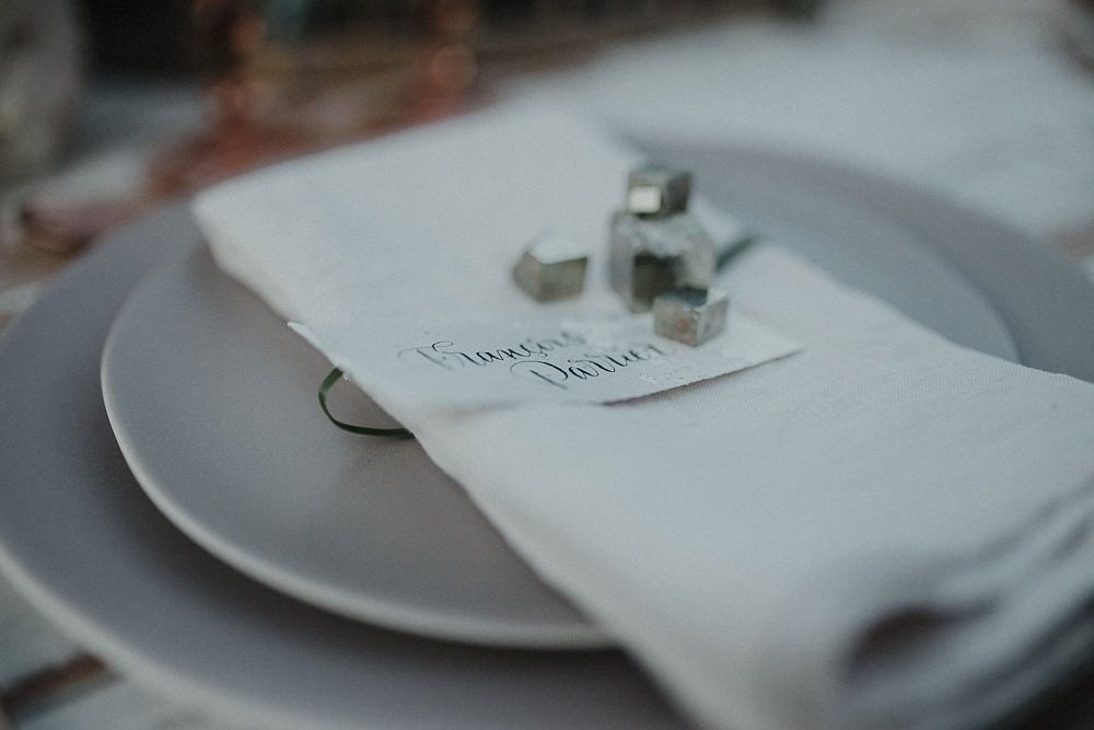 Minimalist place setting with white napkin and small decorative elements on gray plate.