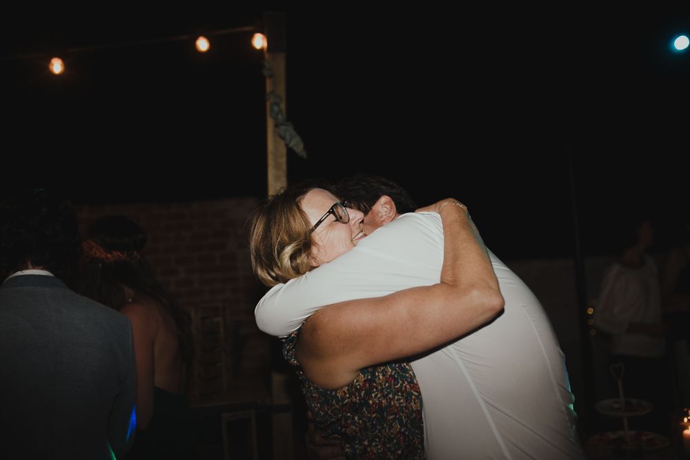 Emotional embrace between two people at a dimly lit wedding reception.