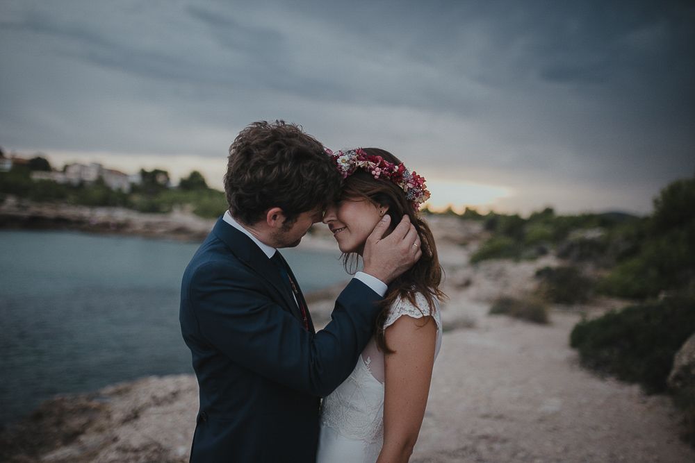 A romantic moment between newlyweds at sunset near the ocean.