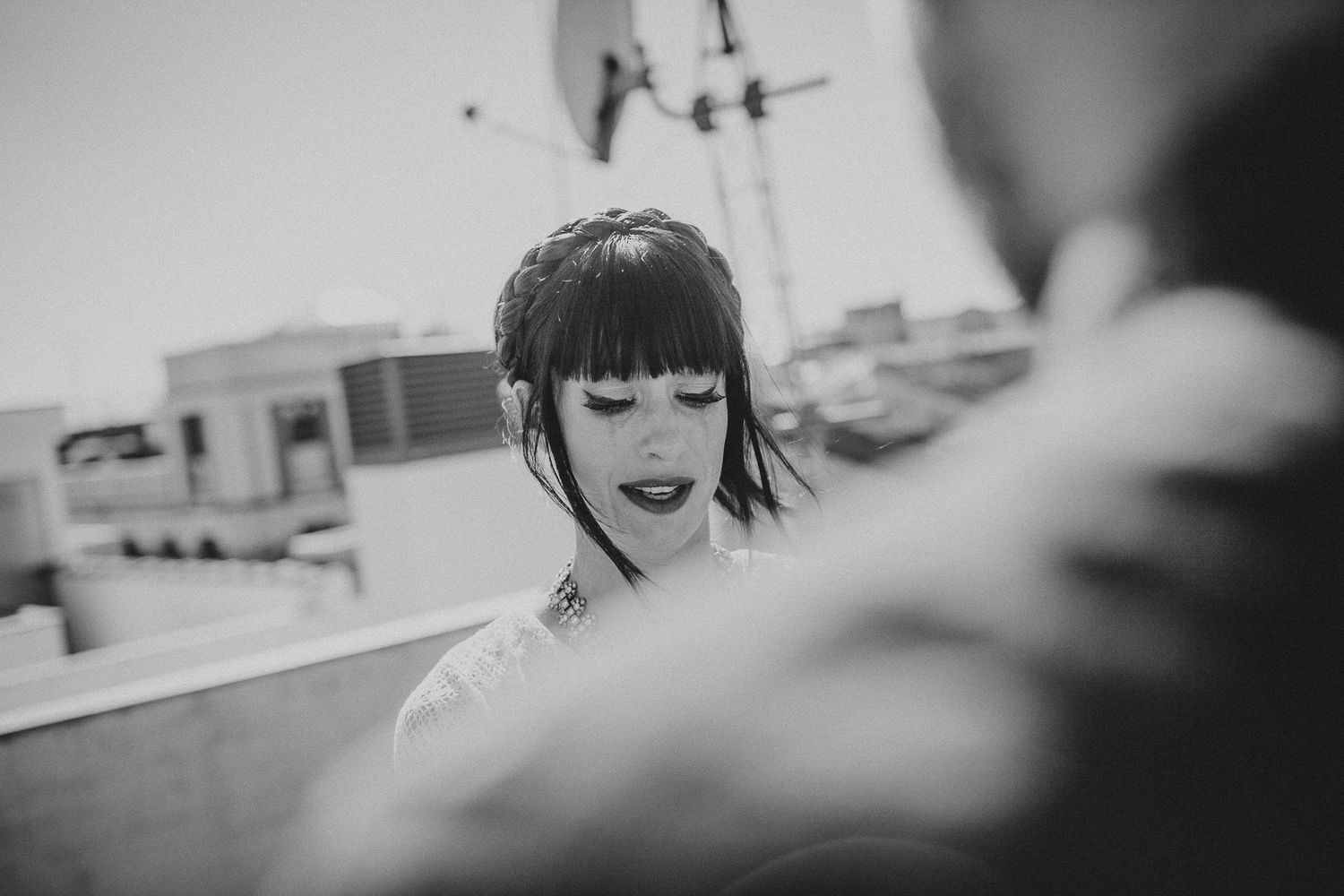 Black and white portrait of a woman in lace dress laughing during an outdoor celebration.