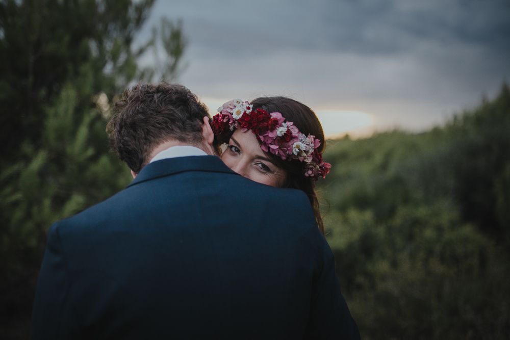 An intimate wedding moment captured from behind against a natural backdrop.