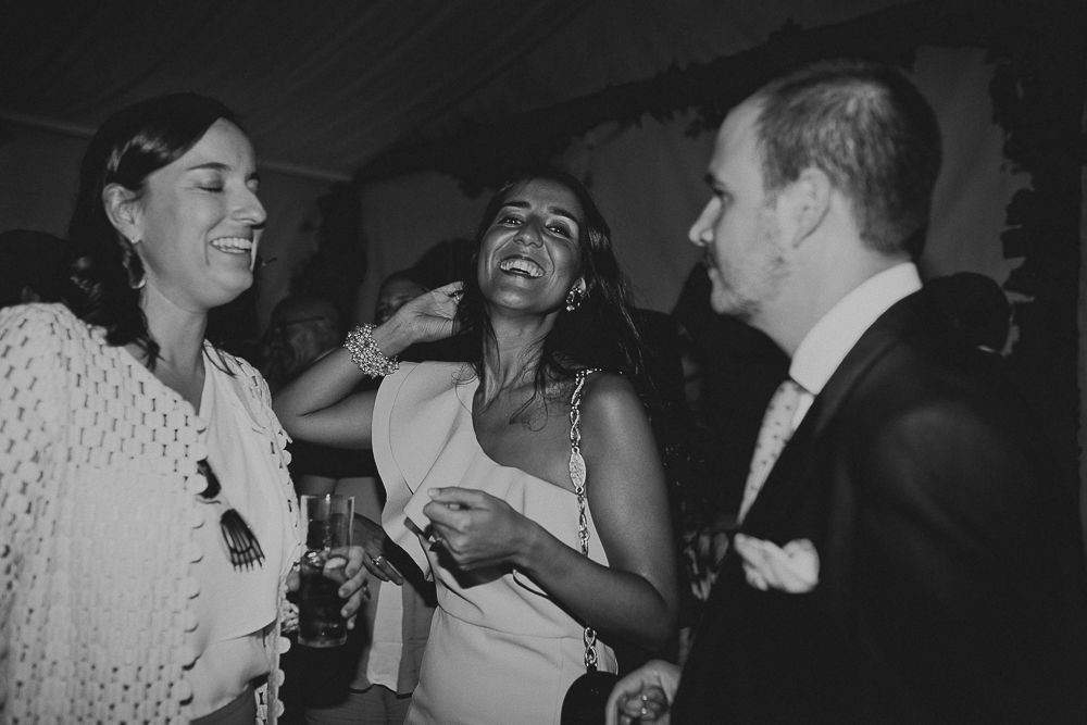 Wedding guests laughing and enjoying themselves during evening reception celebration.
