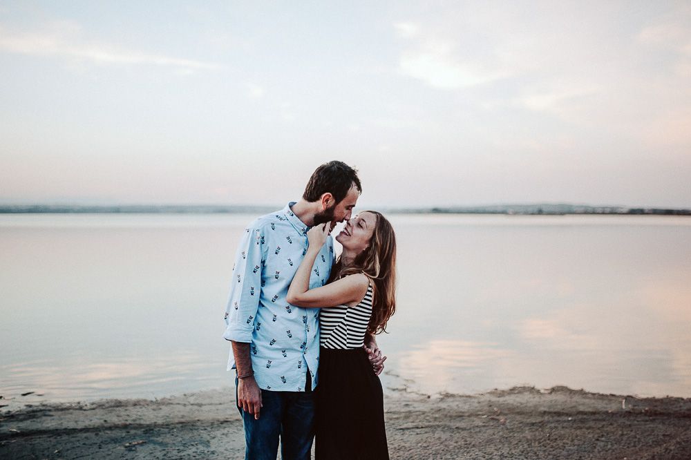 Couple sharing intimate moment on shoreline during sunset.