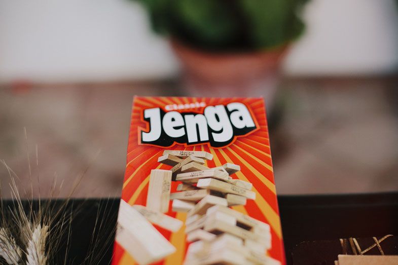 A Jenga game box with orange and white packaging sits on a dark surface with a blurred background.