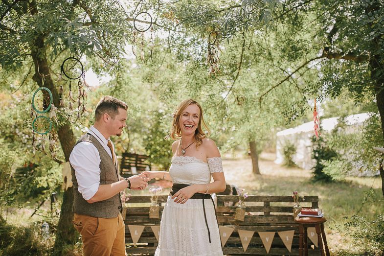 An intimate outdoor wedding celebration with rustic decor and geometric wooden backdrop.