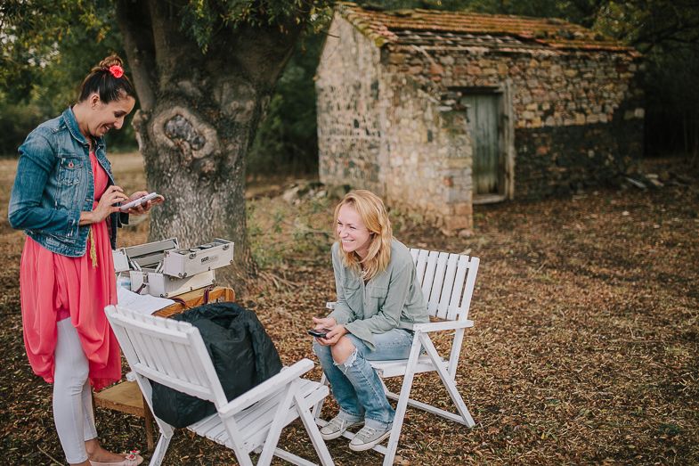 Two friends having a casual outdoor meal near a rustic stone building on a fall afternoon.
