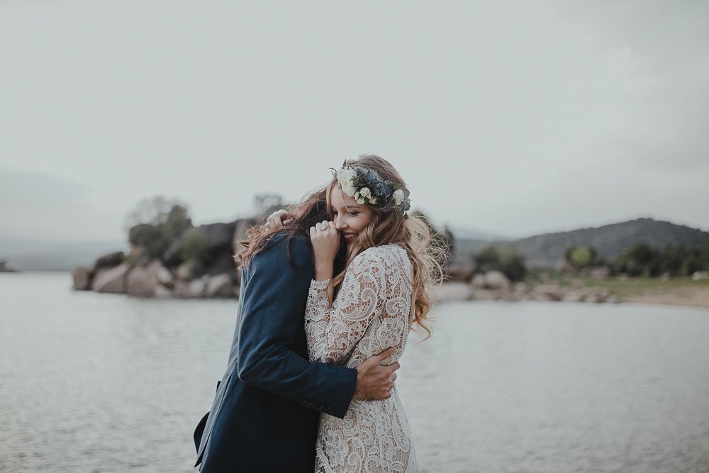Intimate wedding portrait of couple against moody lake and mountain backdrop.
