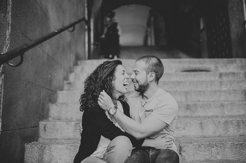 Couple sharing intimate moment on stone steps in black and white photography.
