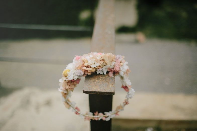 A delicate floral crown made with pink and white flowers sits on a wooden post.