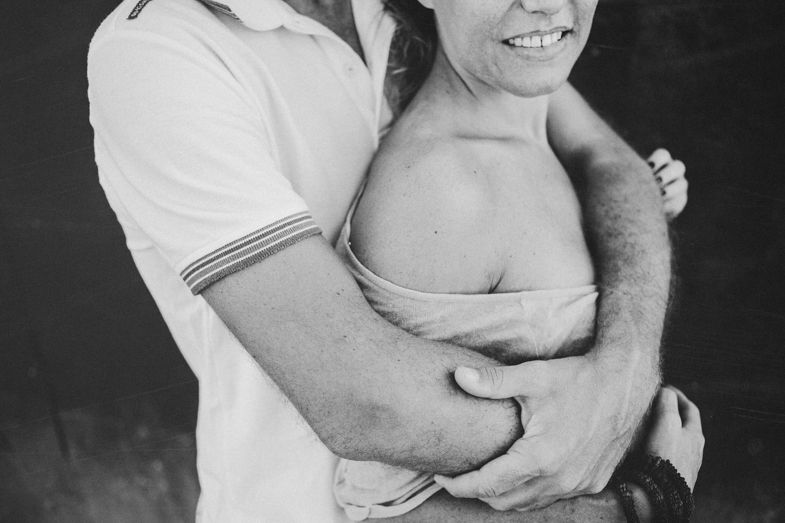 A tender black and white portrait of a romantic embrace against a dark background.