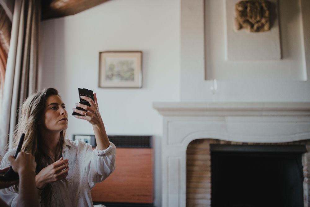 Person holding phone and coffee cup by a white fireplace.