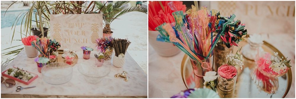 Colorful tropical wedding reception table setting with pink flowers and vintage glassware on beige table runner.