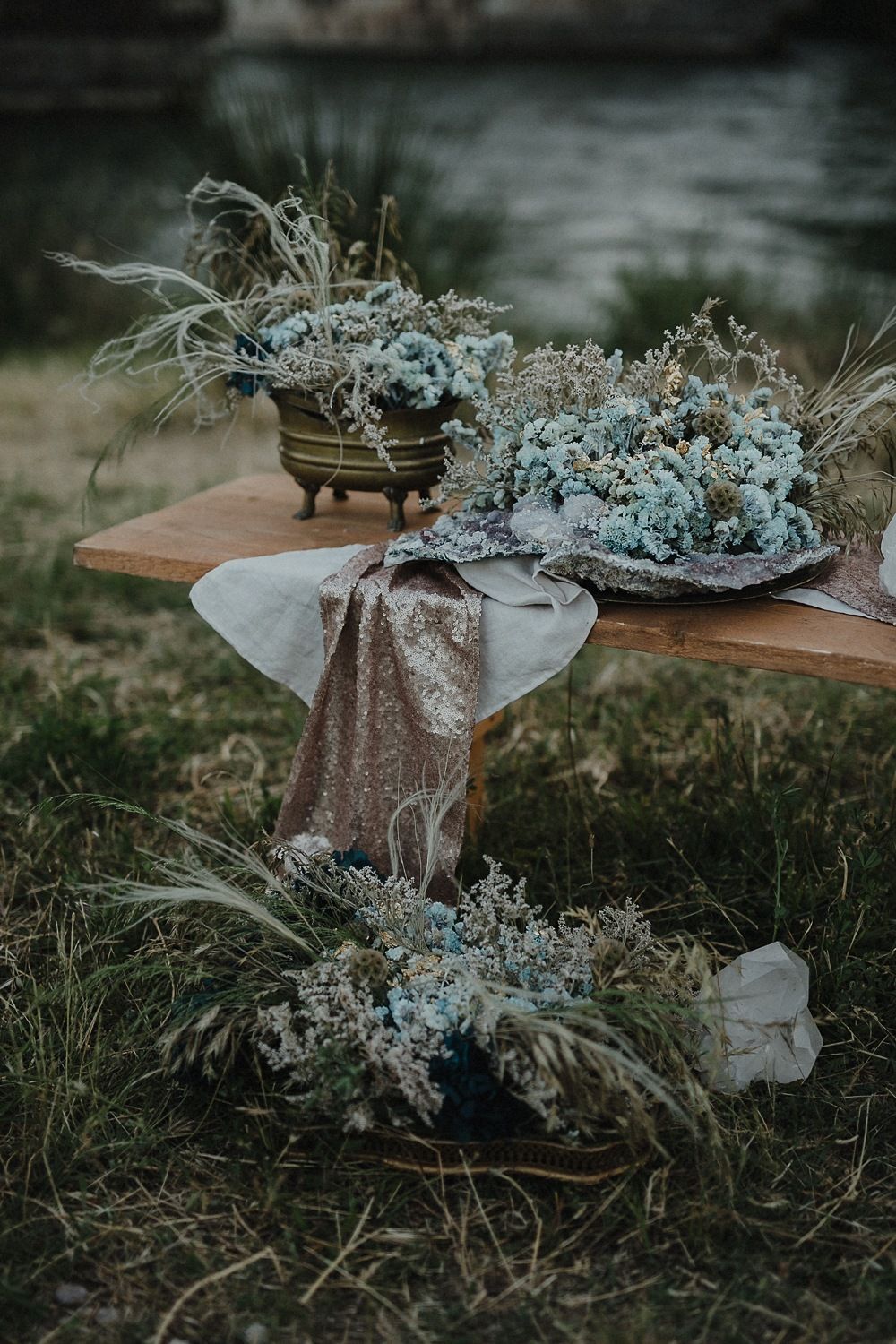 Moody outdoor table styling with dried blue florals and metallic accents.