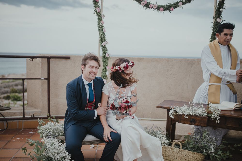 Wedding ceremony under a floral arch on a rooftop venue with mountain views.