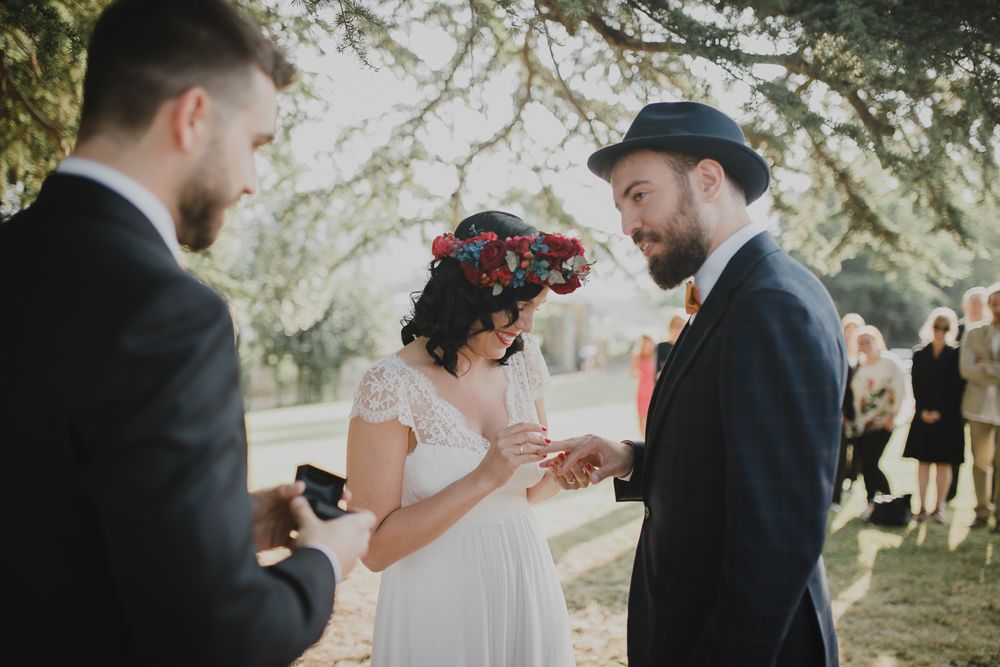 A romantic outdoor wedding ceremony with a floral crown and traditional vows being exchanged.