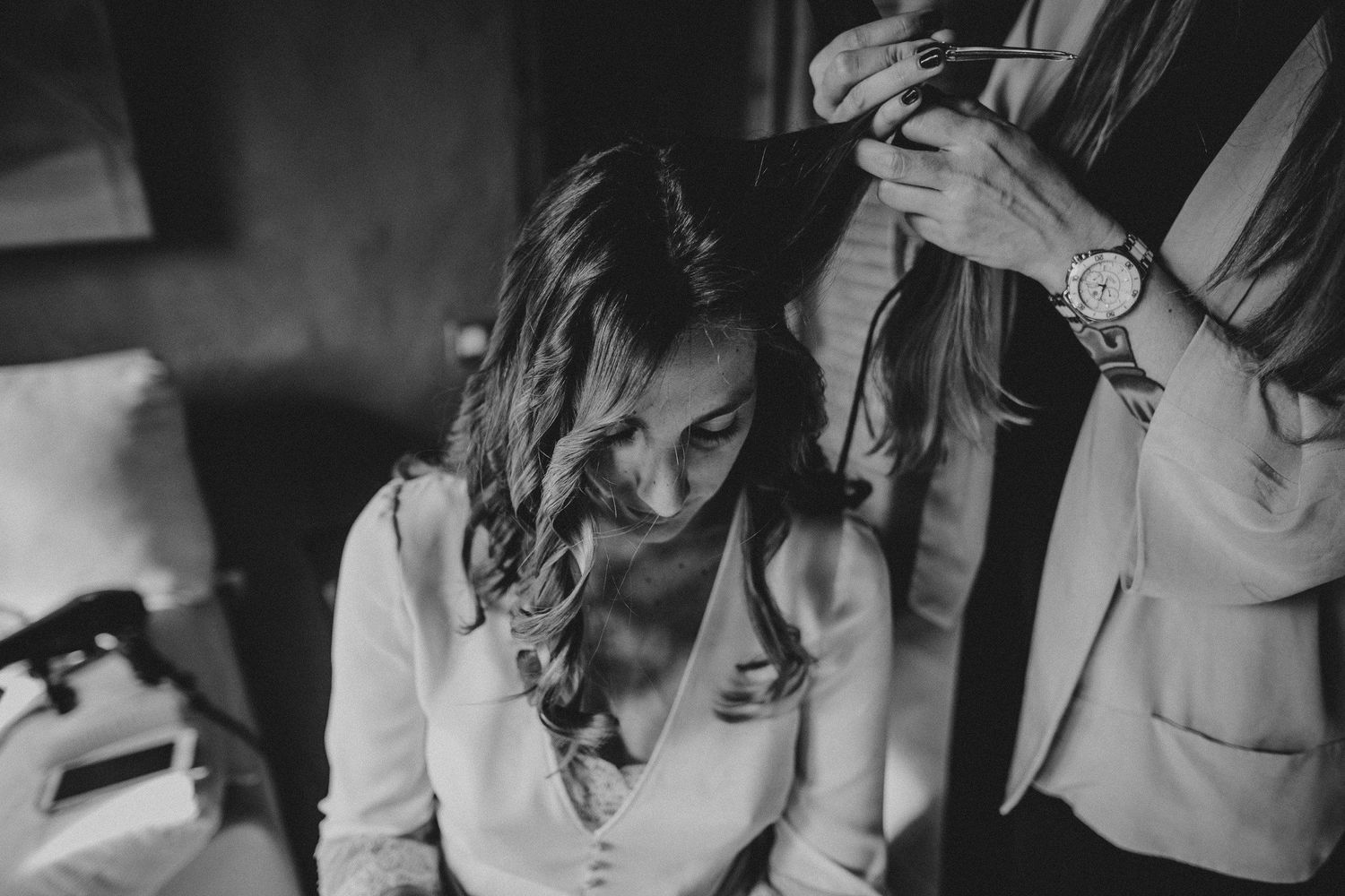 A black and white wedding preparation photo of someone having their hair styled.