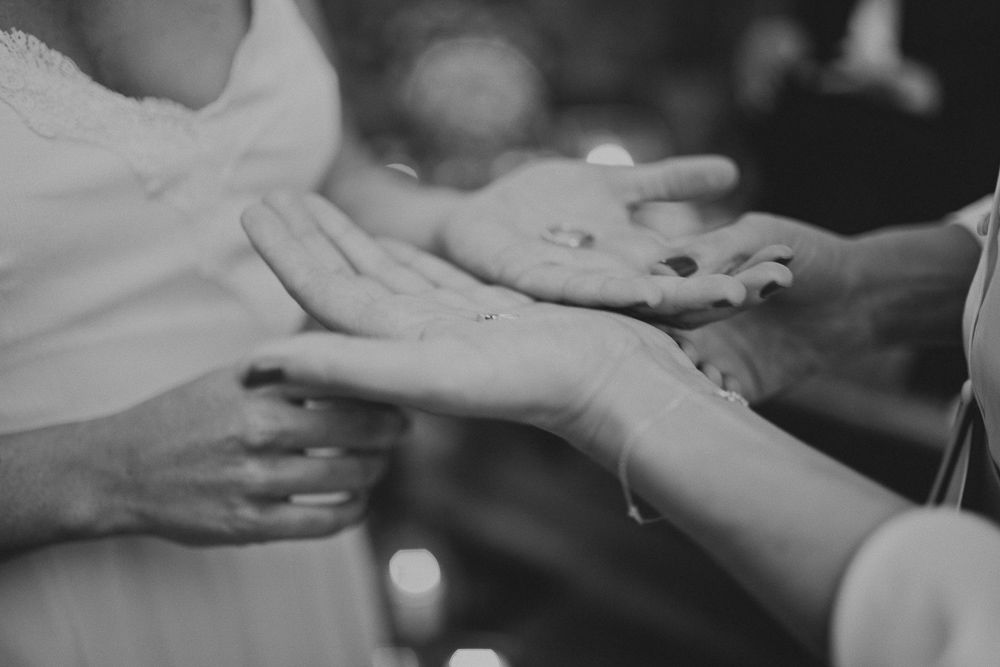 Close-up black and white shot of hands exchanging rings during a wedding ceremony.