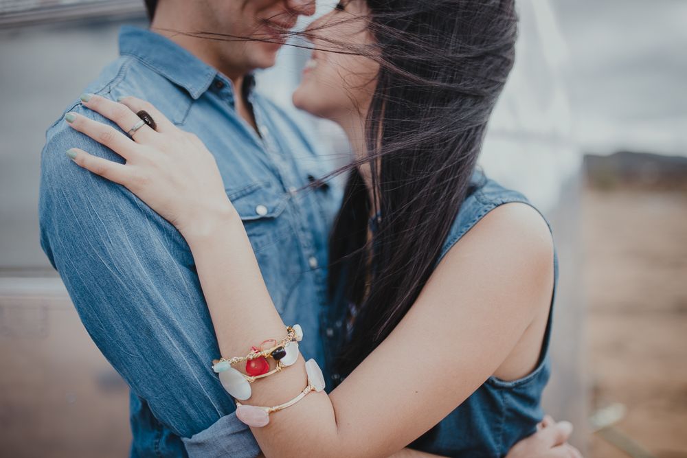 Close-up shot of an embrace beside an Airstream, focusing on hands with bracelets.