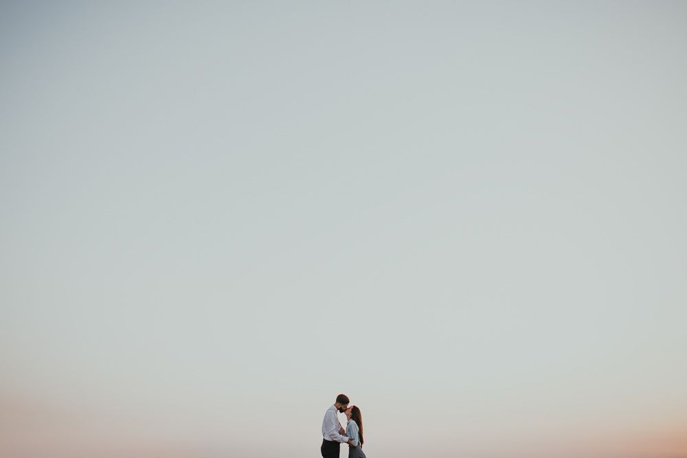 Minimalist silhouette of two people against pale sky at sunset.