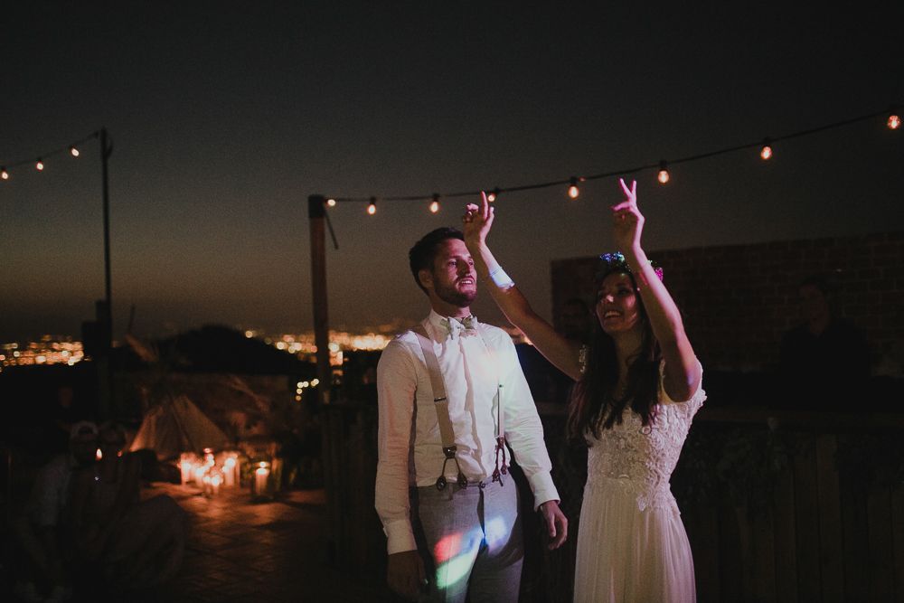 Newlyweds dancing under twinkling lights at their evening reception.