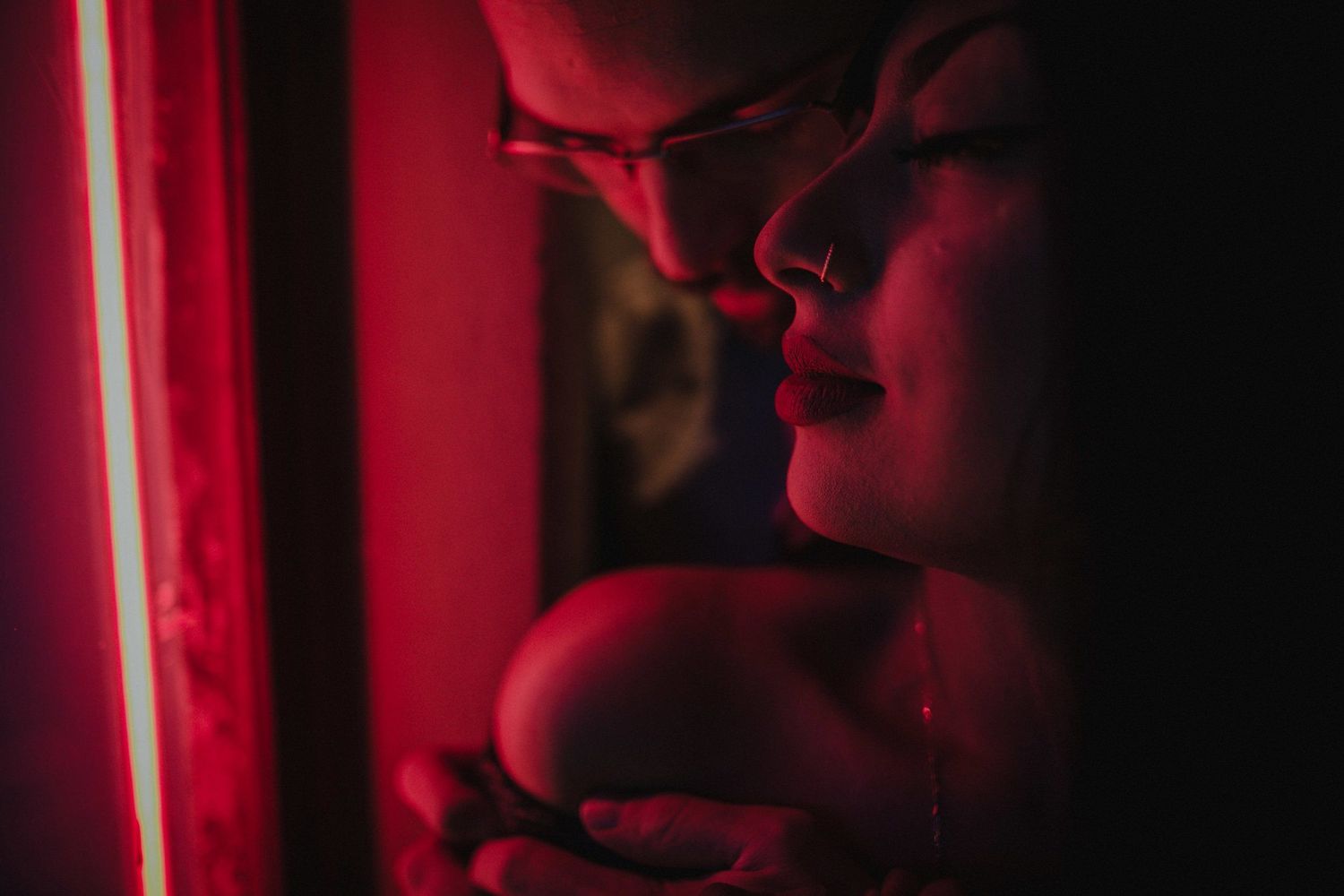 Dramatic red-lit portrait capturing an intimate moment in low light.