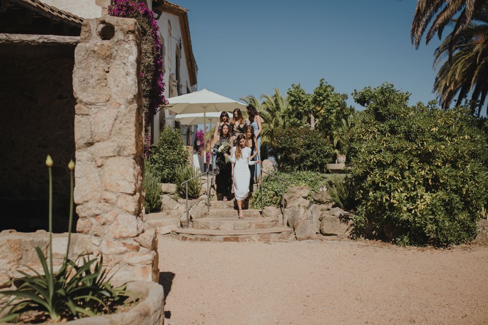 Group walking along a rustic stone building path on a sunny day.