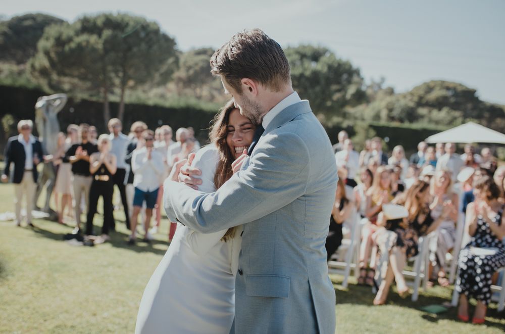 Newlyweds share intimate moment during outdoor garden wedding as guests look on.